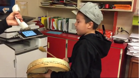 Jerome Whiteknife, grade 4 student, plays the drum and sings to students, parents and staff during morning announcements as a way to open minds.
